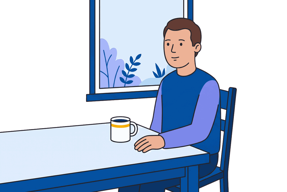 A man sitting with a cup of tea at his kitchen table