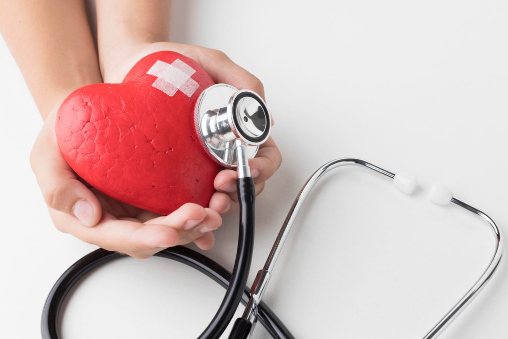A person with a stethoscope holds a red heart, representing compassion and the TPD Helpline's support services.

