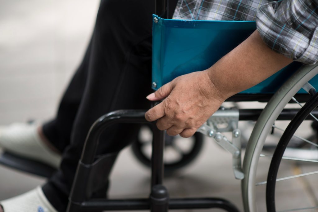 Close-up-of-senior-woman-hand-on-wheel-of-wheelchair-during-walk-in-hospital